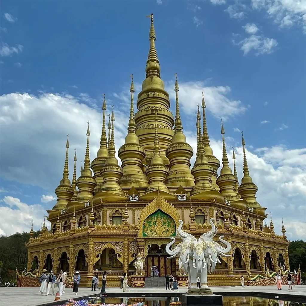 Mengle Grand Buddha Temple 在 勐泐大佛寺,金碧輝煌的佛塔群層層疊起,白象雕塑佇立前方,建築融合南傳佛教風格,氣勢宏偉莊嚴。