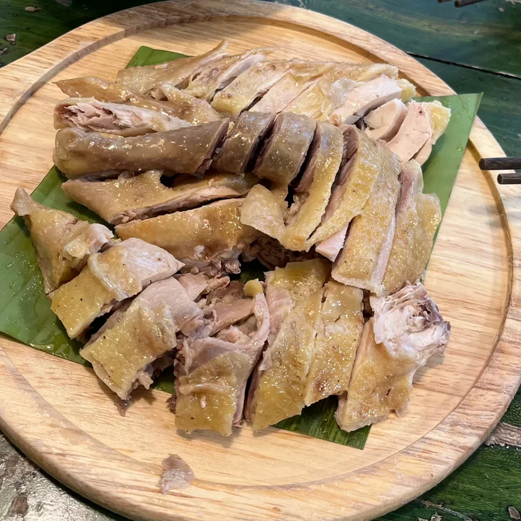Yuanyang Hani Dipping Chicken 地道元陽哈尼蘸水雞,雲南特色料理。嫩白切雞切片盛於木盤,鋪上芭蕉葉,搭配香辣蘸水。