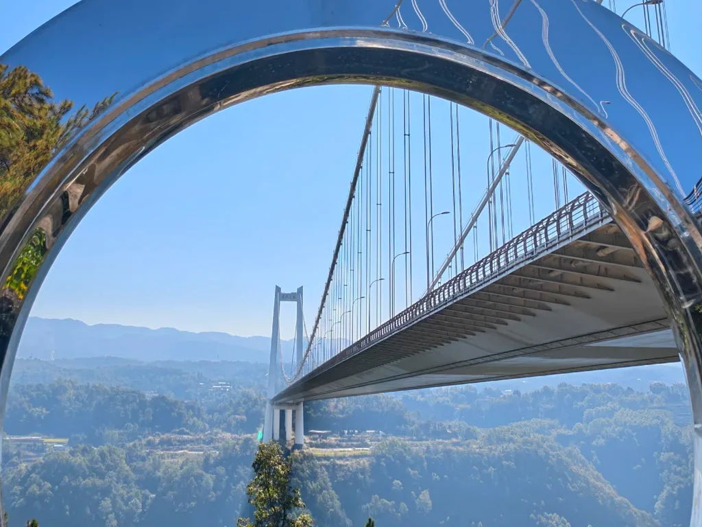 騰衝龍江大橋,橫跨龍江河谷的亞洲高橋,透過景觀平台的鏡面拱門取景,拍出科幻感十足的橋體全景。