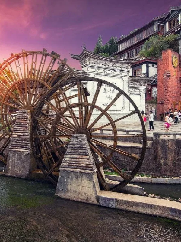 Lijiang Ancient Town 麗江古城著名的大水車景觀,巨大的木製水車在清澈河道旁緩緩轉動,周圍是傳統納西族建築與古城街景。
